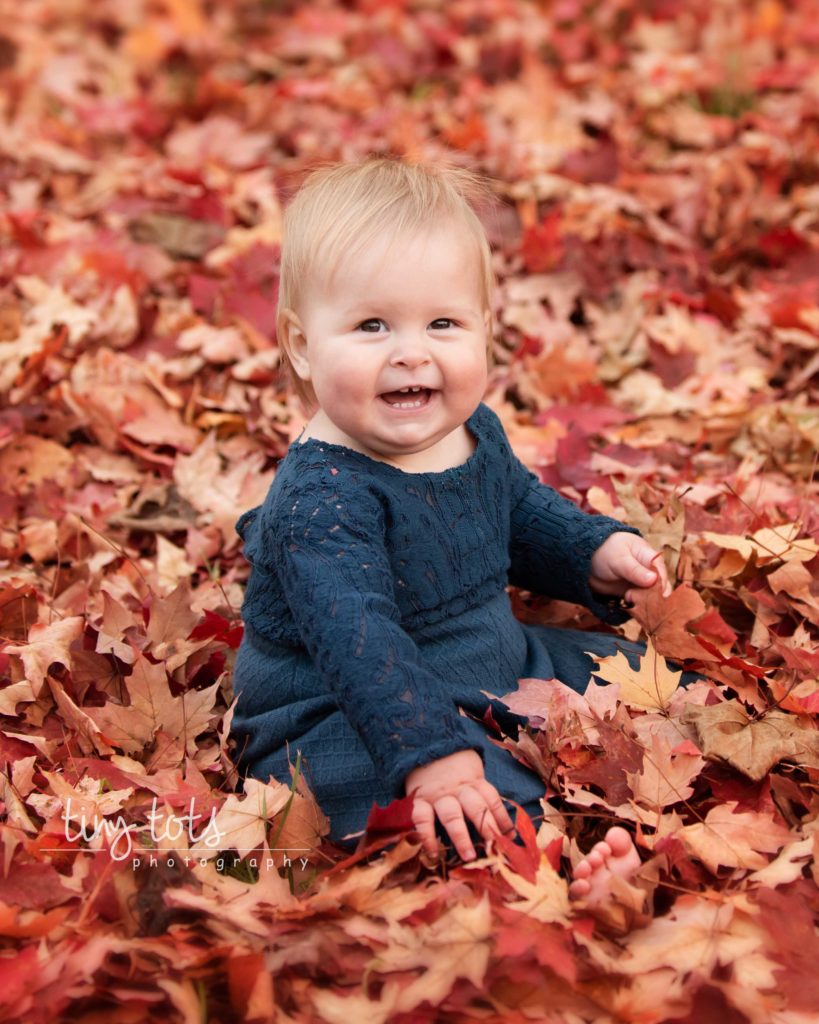 baby-girl-sitting-leaf-pile-fall